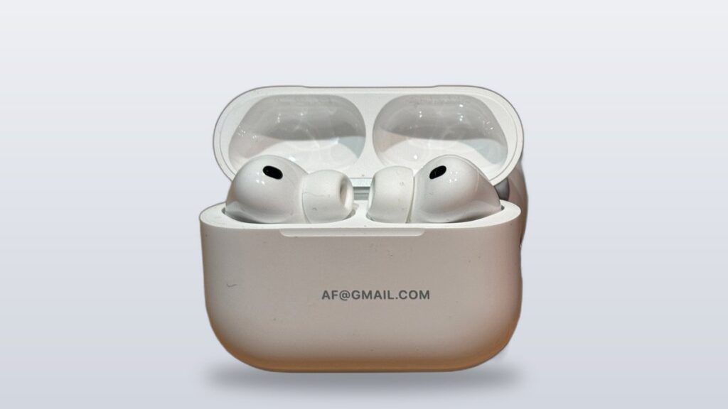 Real Apple AirPods Pro 3 earbuds in their open charging case, all-white stems with dark mic dots
