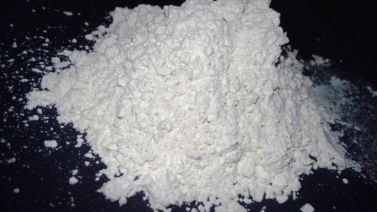 A pile of fine white food-grade diatomaceous earth powder on a dark surface
