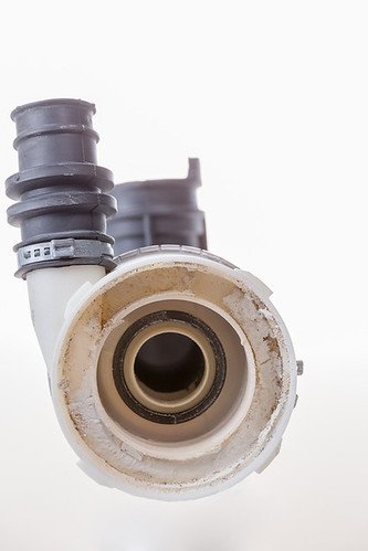 White limescale calcification crusted inside the drain fitting of a dishwasher