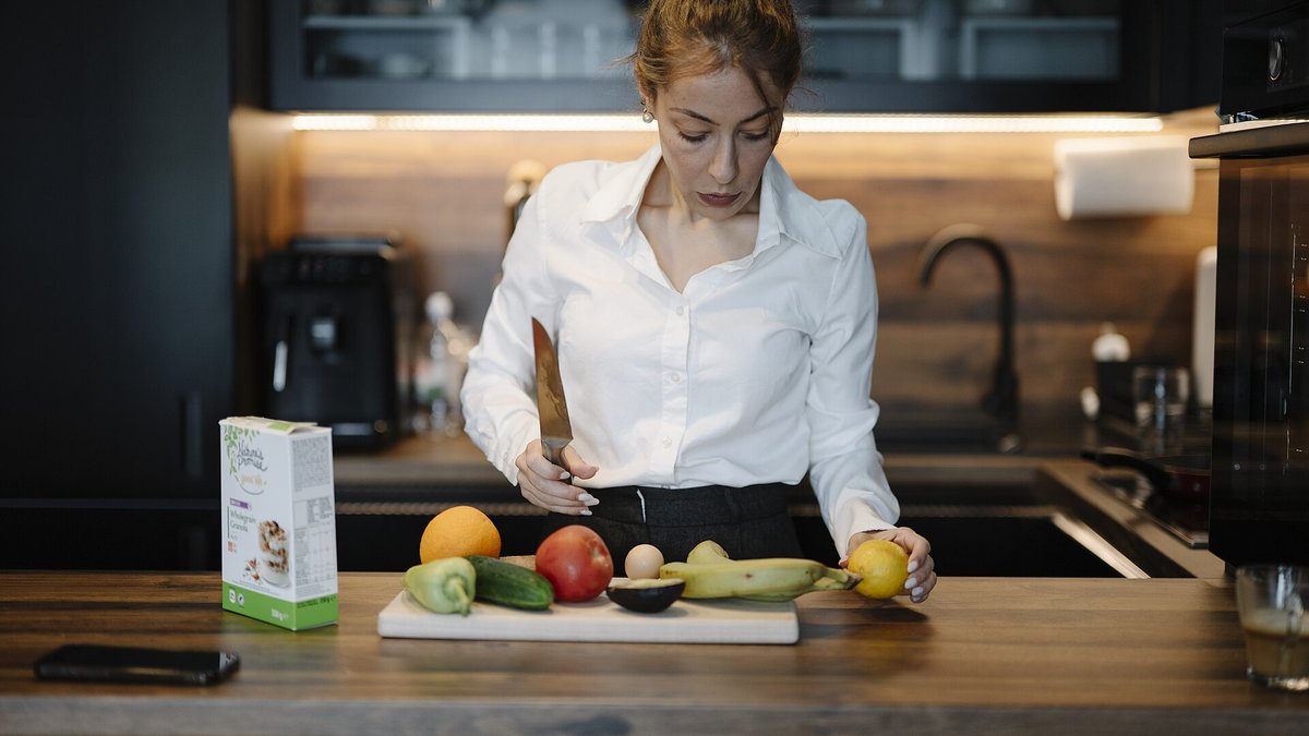 A person preparing fresh fruits and vegetables at a kitchen counter, part of a routine that keeps fruit flies from breeding