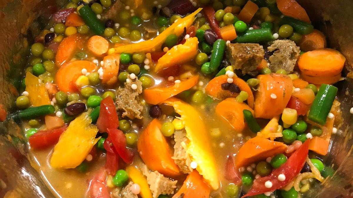 A vegetable stew with peas, carrots and green beans cooked inside an Instant Pot inner pot