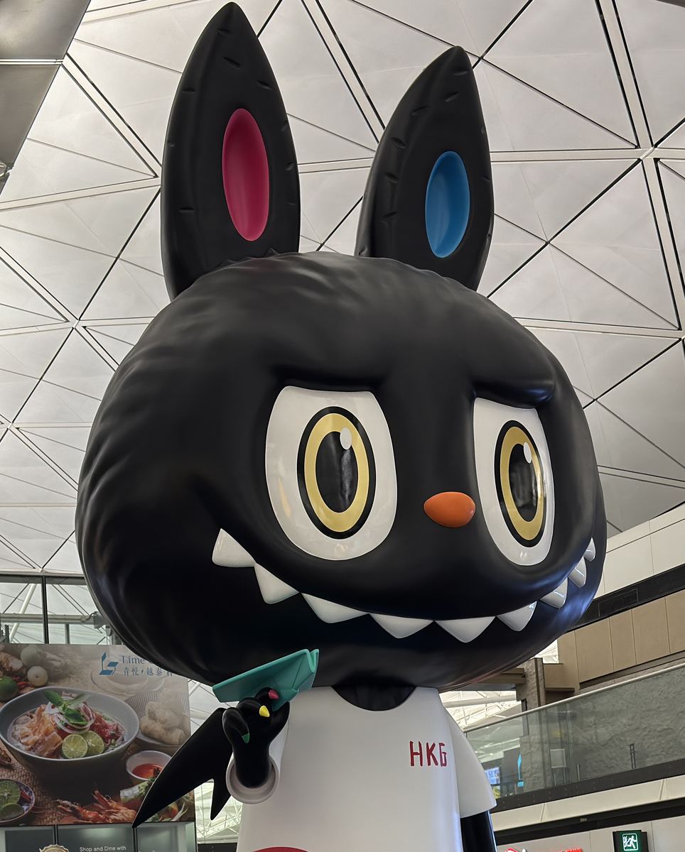 Giant The Monsters character installation at Hong Kong International Airport showing tall close-set ears and a wide toothy grin