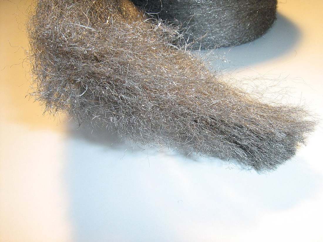 A pad of coarse steel wool being pulled from a roll, the material used to pack gaps so mice cannot chew through