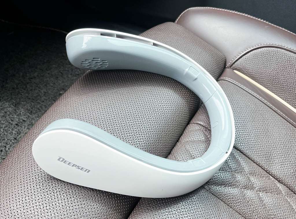White bladeless U-shaped neck fan resting on a car seat, the wearable personal fan that hangs around your neck