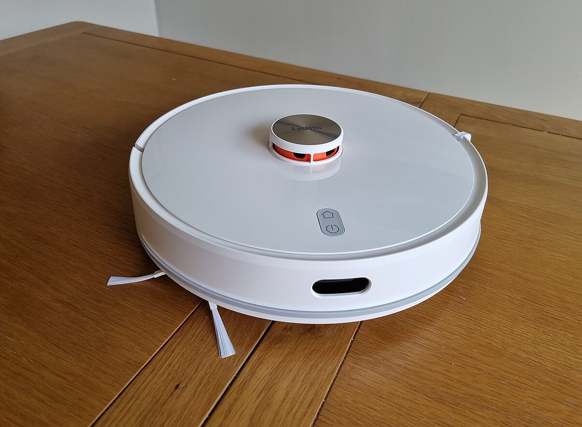 A white robot vacuum with a lidar navigation turret cleaning a hardwood floor