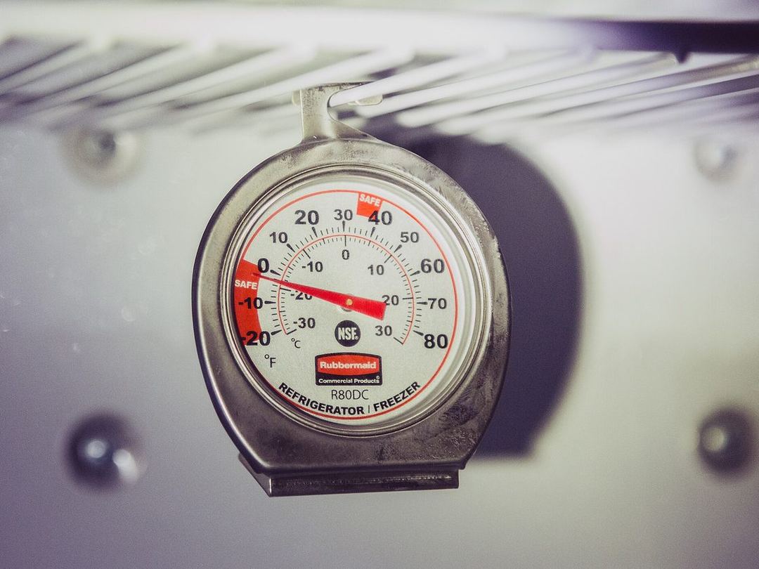 A Rubbermaid refrigerator thermometer clipped to a wire shelf, its needle in the safe zone below 40 degrees Fahrenheit
